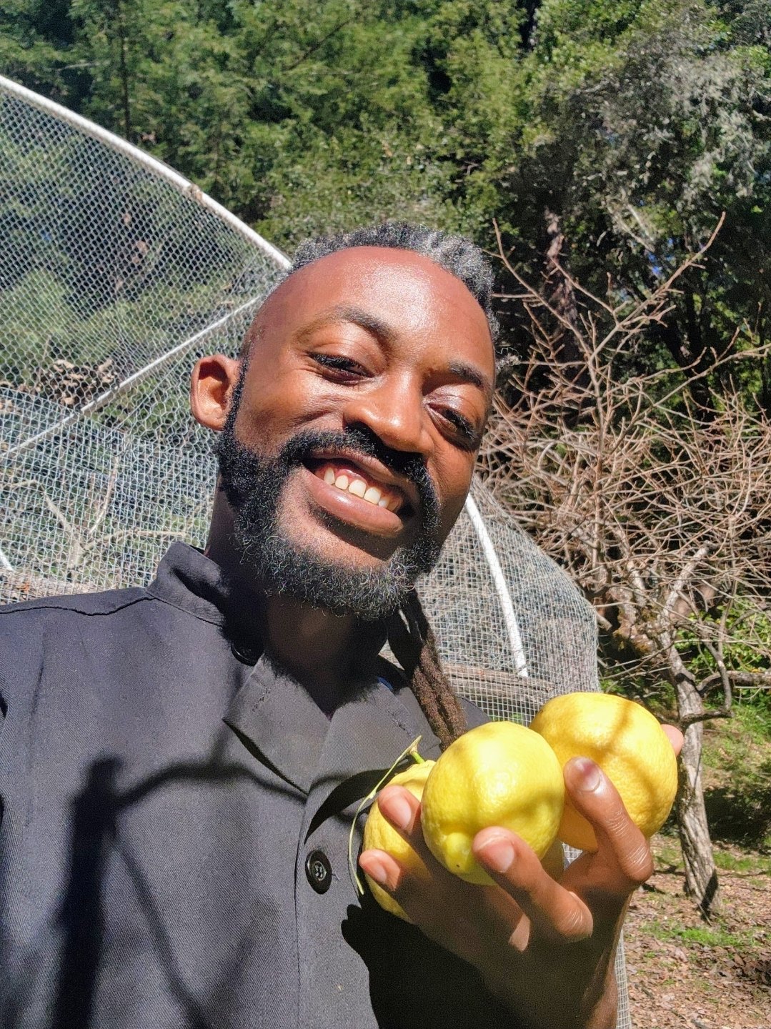 Terry smiling outdoors, holding fresh lemons